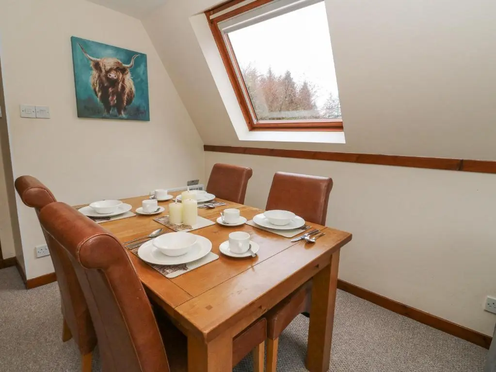a wooden dining room table with chairs and a window at Lodge 2 - Inglewood Lodge in Spean Bridge