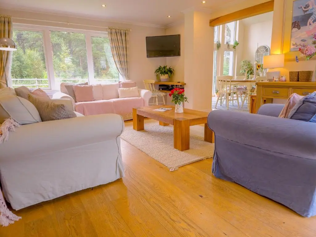 a living room with two couches and a table at The Bellhouse - hot tub lodge in Tomatin in Tomatin