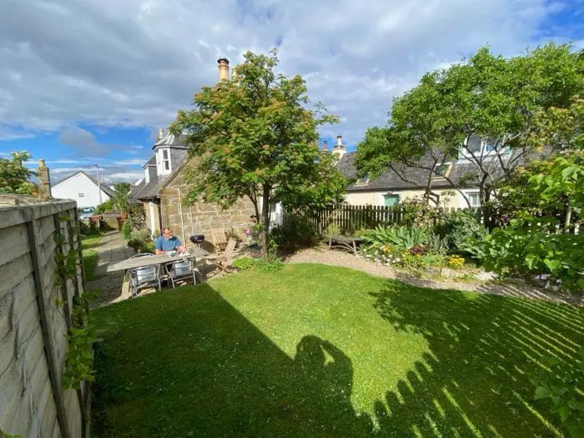 a person sitting at a table in a garden at Myrtle Cottage Findhorn in Forres