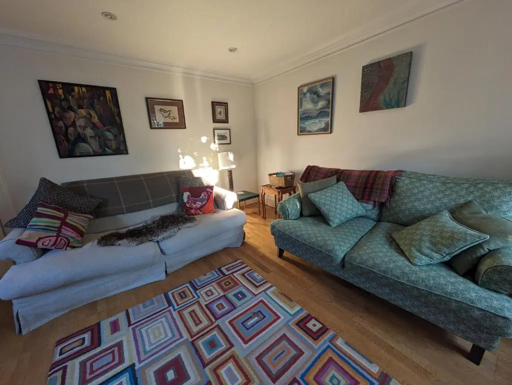 a living room with two couches and a rug at Myrtle Cottage Findhorn in Forres