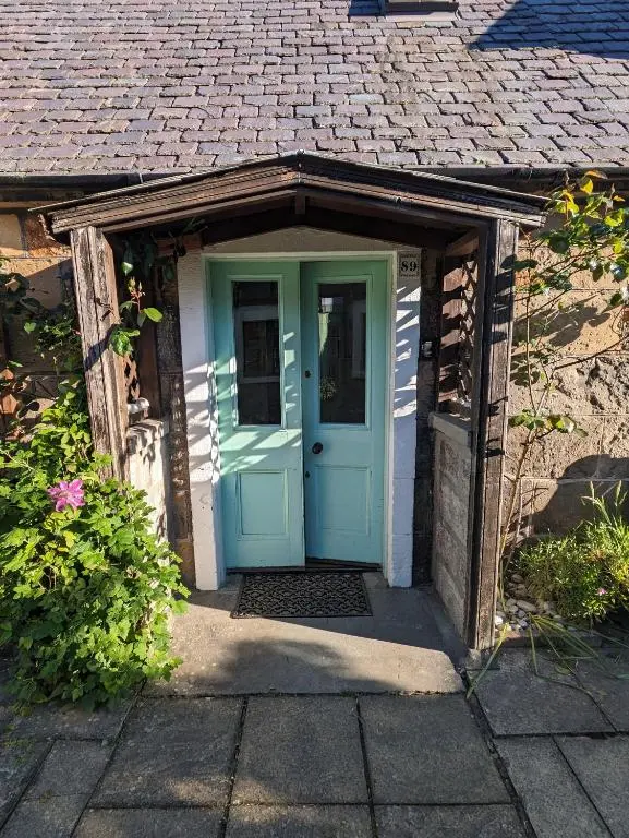 a small house with a blue door in it at Myrtle Cottage Findhorn in Forres