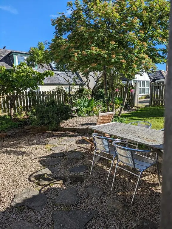 a wooden table and chairs in a yard at Myrtle Cottage Findhorn in Forres