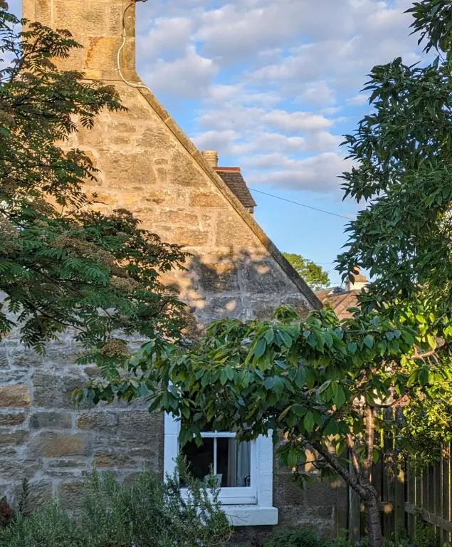 a brick building with a chimney and trees at Myrtle Cottage Findhorn in Forres