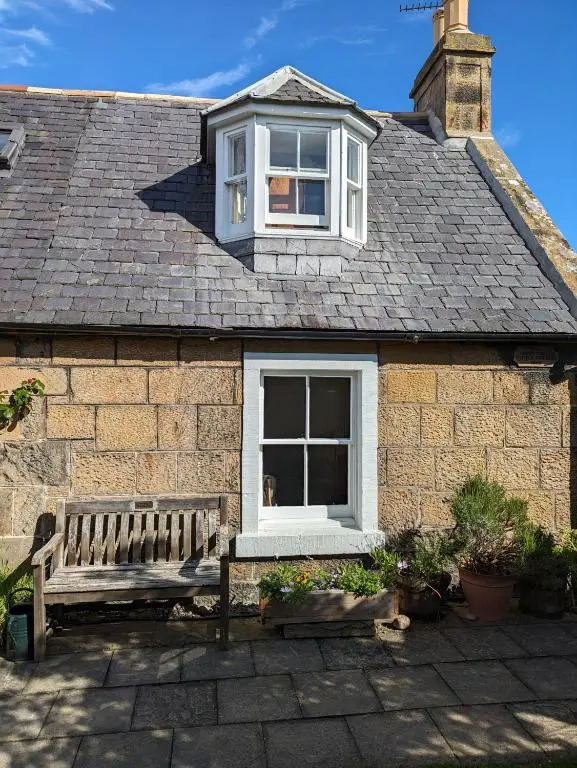 a house with a bench in front of a window at Myrtle Cottage Findhorn in Forres