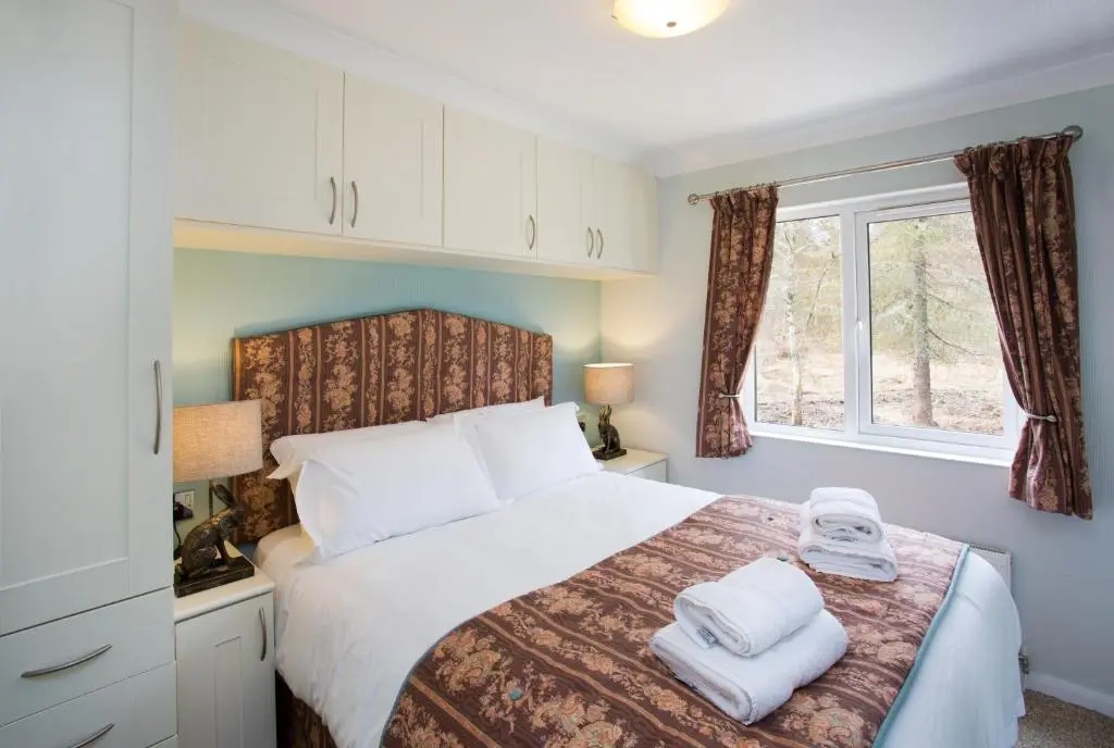 a bedroom with a bed with towels on it at Bluebell Lodge - Sleeps 4 Loch & Woodland in Strathpeffer