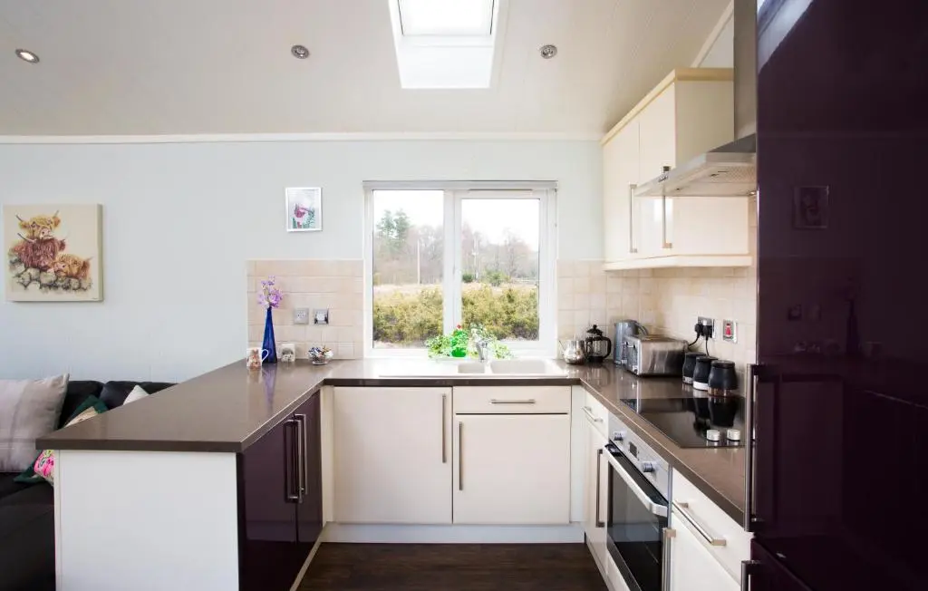 a kitchen with white cabinets and a window at Bluebell Lodge - Sleeps 4 Loch & Woodland in Strathpeffer
