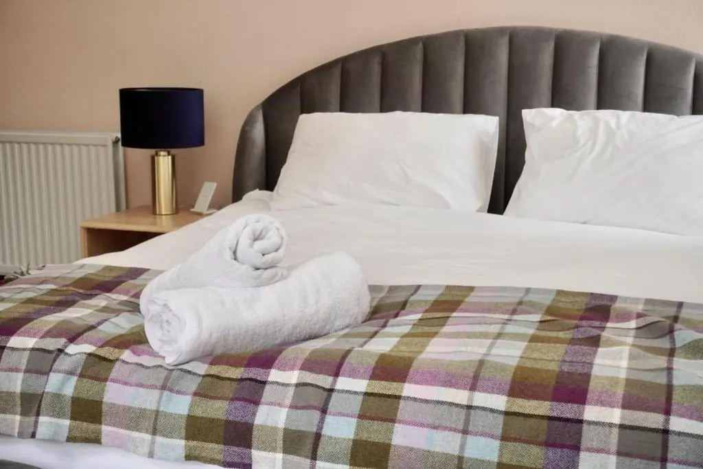 a bed with a pile of towels on it at Ardchoile in Kingussie
