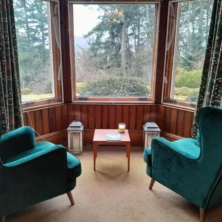 a room with two chairs and a table and a window at Ardchoile in Kingussie