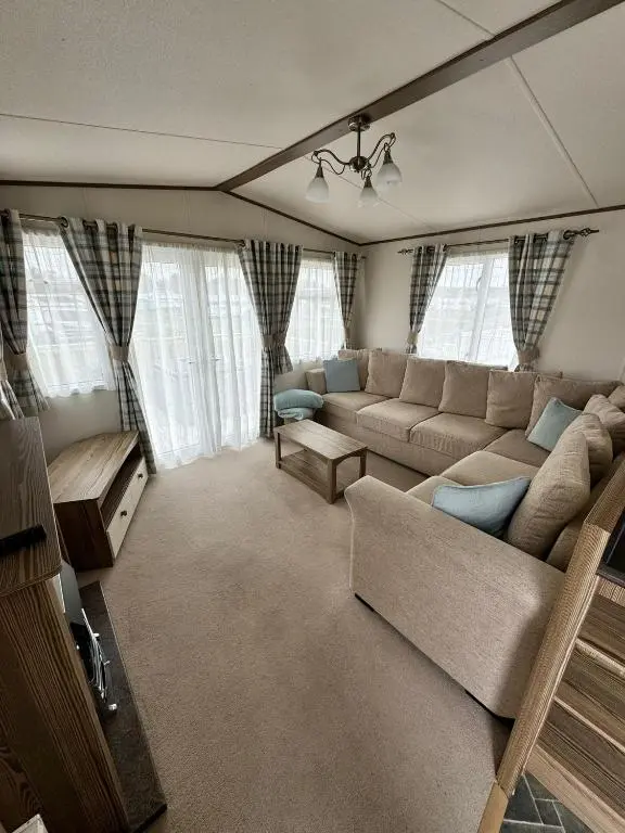 a living room with a couch and a table and windows at Jandor Retreat in Lossiemouth
