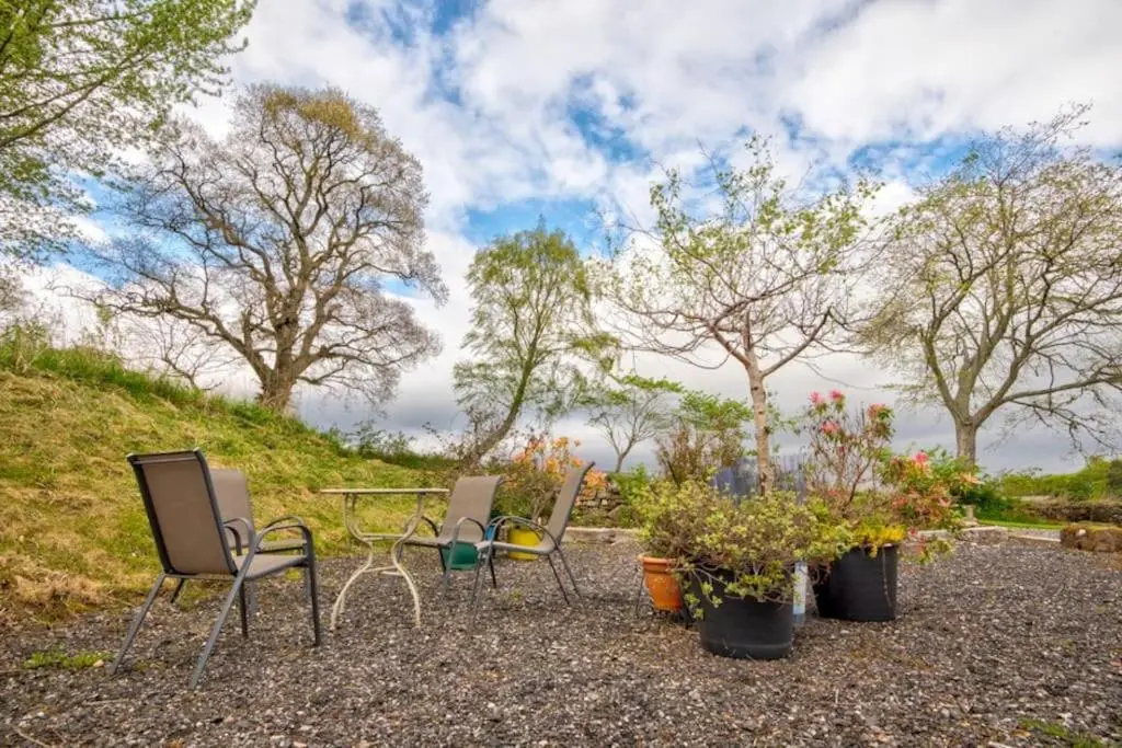 three chairs and a table and some plants and trees at Foulis Cottage, Foulis Estate, Highland Scotland in Ardullie