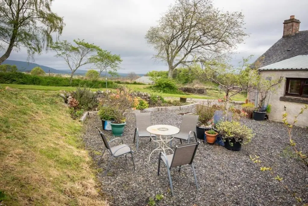 a patio with a table and chairs in a yard at Foulis Cottage, Foulis Estate, Highland Scotland in Ardullie