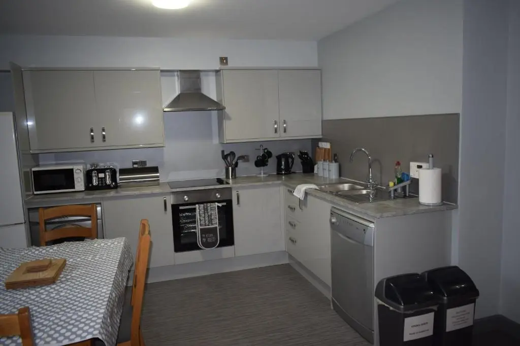 a kitchen with white cabinets and a sink and a table at Dunroamin Self-Catering Apartment in Aviemore