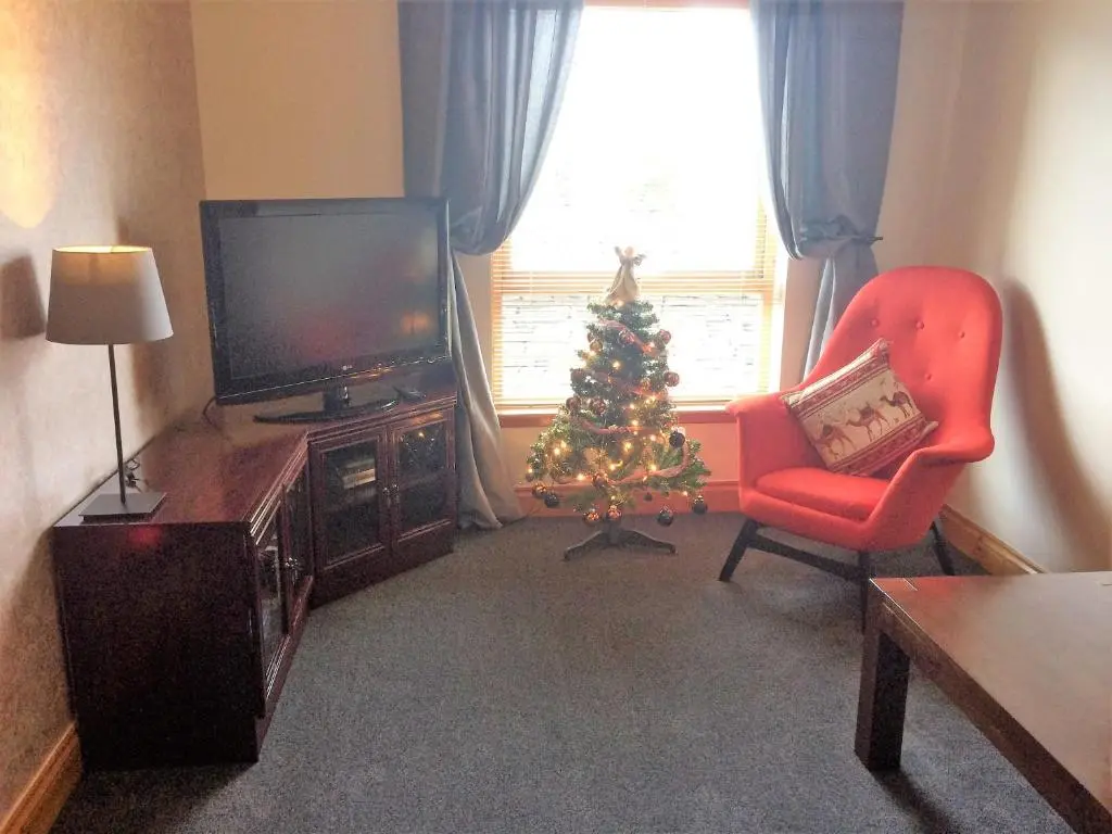 a living room with a christmas tree and a television at Dunroamin Self-Catering Apartment in Aviemore