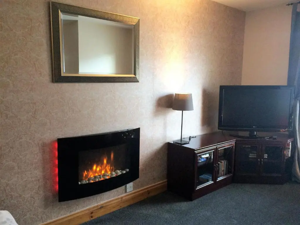 a living room with a fireplace and a tv at Dunroamin Self-Catering Apartment in Aviemore