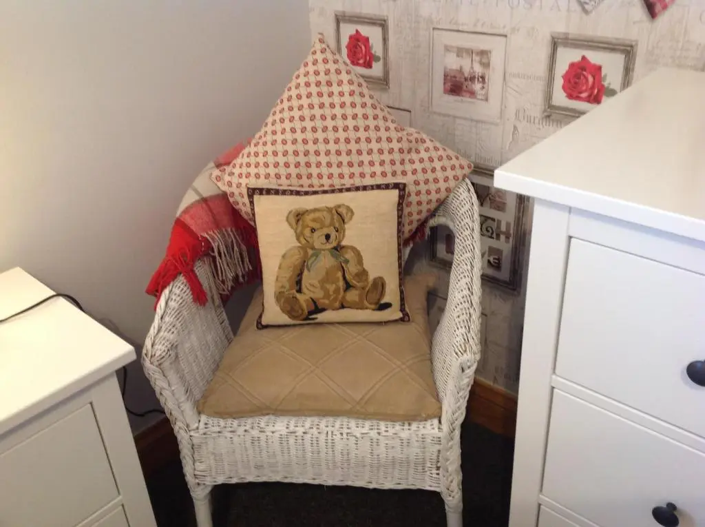 a teddy bear sitting in a chair with a pillow at Dunroamin Self-Catering Apartment in Aviemore