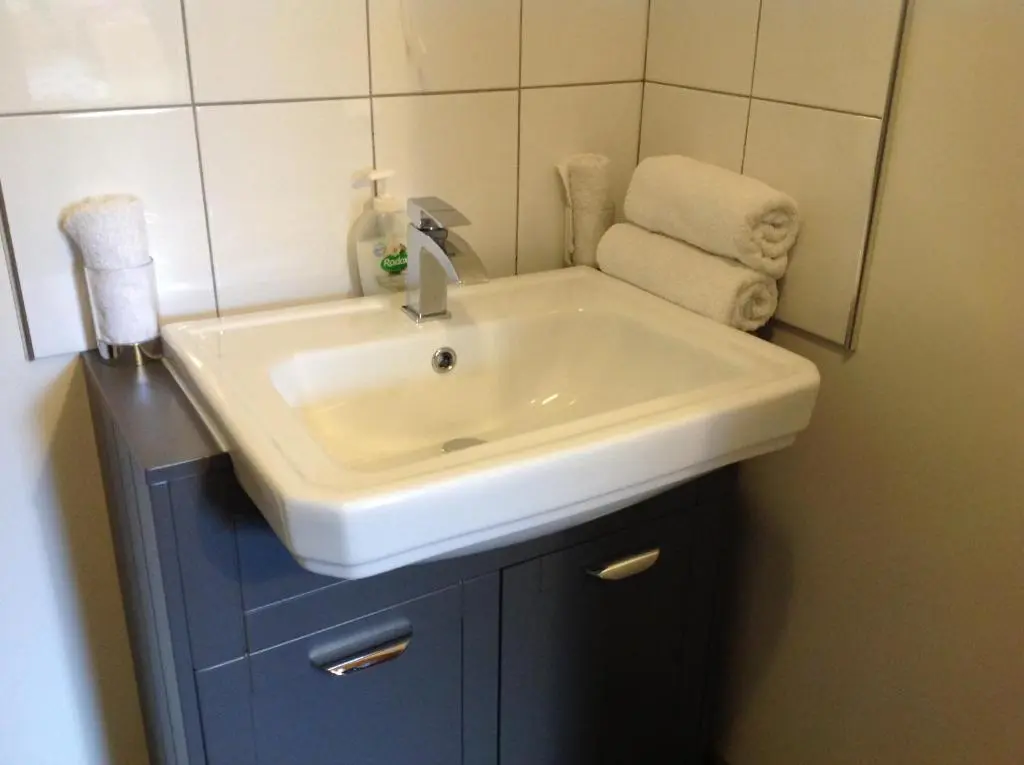 a bathroom with a white sink and a mirror at Dunroamin Self-Catering Apartment in Aviemore