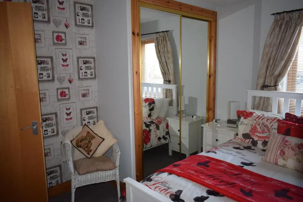 a bedroom with a bed and a mirror at Dunroamin Self-Catering Apartment in Aviemore