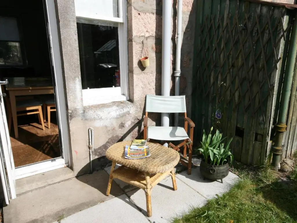 a chair and a table in front of a house at Viewington Lodge in Ballater