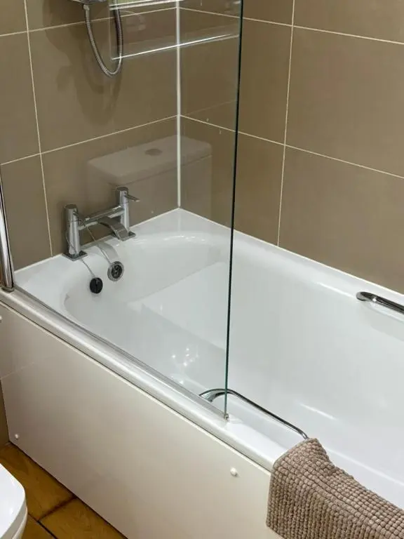 a white bath tub with a glass shower door at Craigie View Aviemore in Aviemore