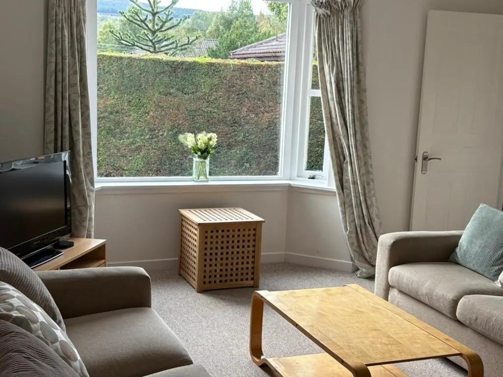 a living room with a couch and a large window at Craigie View Aviemore in Aviemore