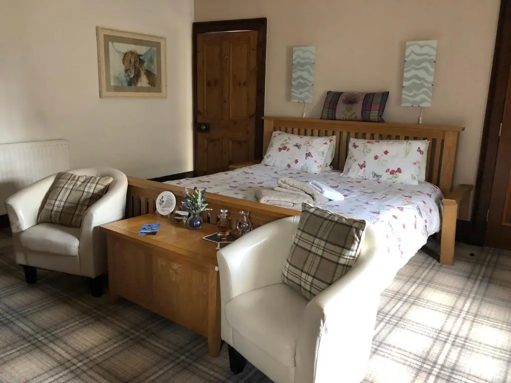 a bedroom with a bed and a couch and a chair at Haus Alba in Grantown on Spey