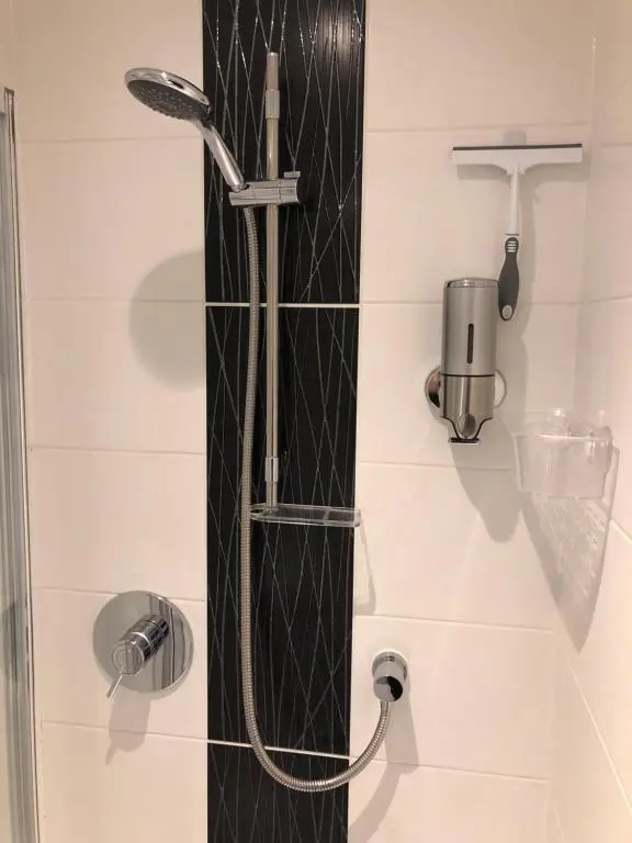 a shower in a bathroom with a black and white wall at Haus Alba in Grantown on Spey
