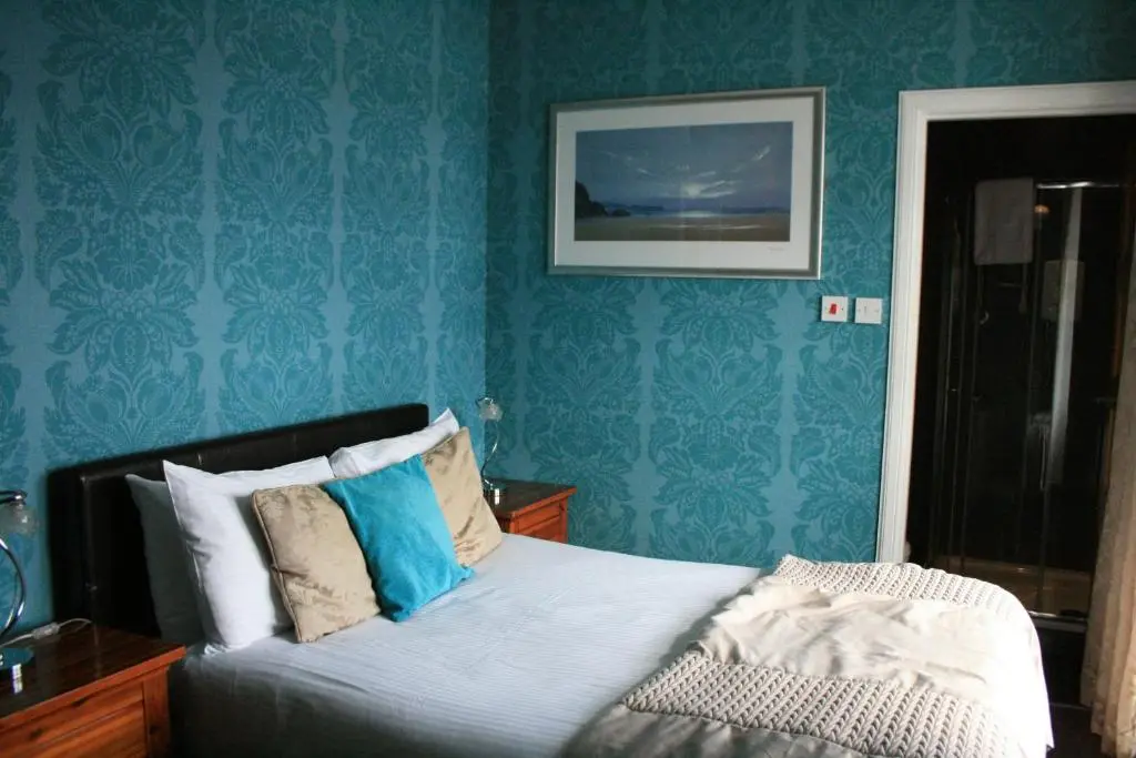 a bedroom with blue walls and a bed with pillows at North Kessock Hotel in Inverness