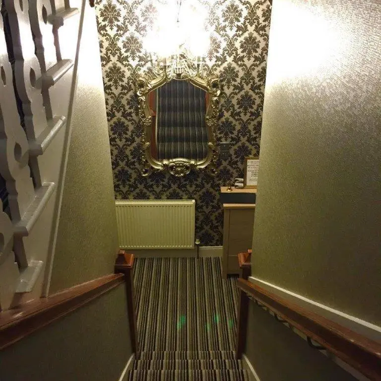 a hallway with a staircase with a mirror on the wall at North Kessock Hotel in Inverness