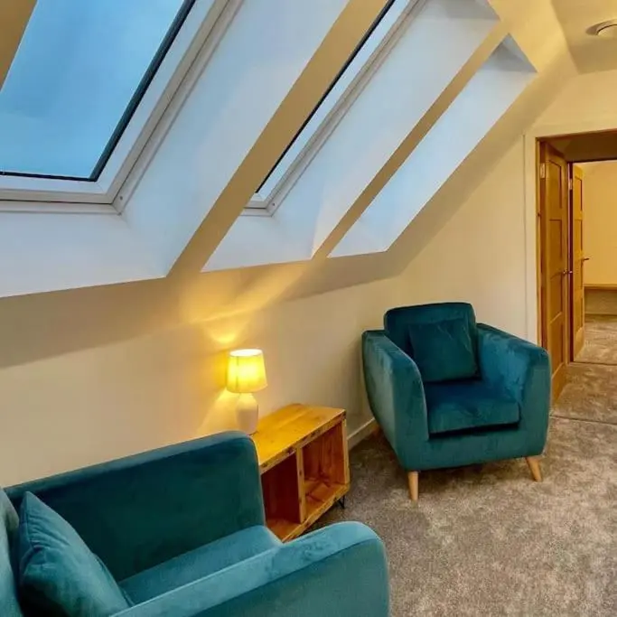 a living room with two blue chairs and a table at The Clearing in Huntly