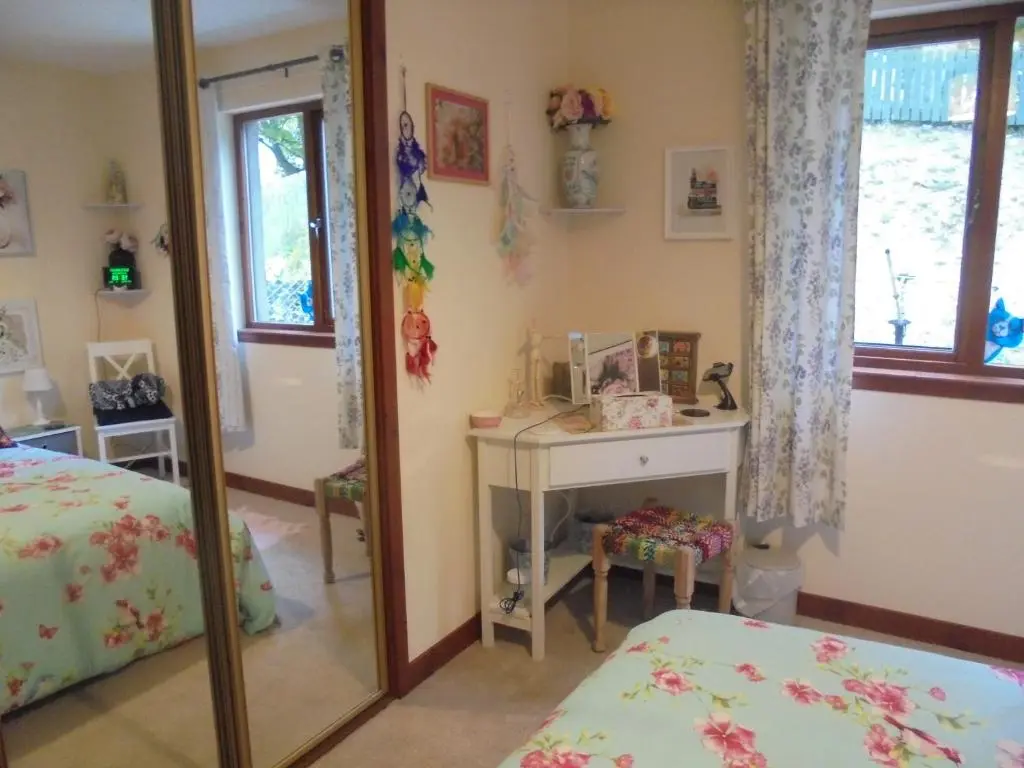 a bedroom with a mirror and a table and a bed at 3 Station Court, Munlochy in Munlochy