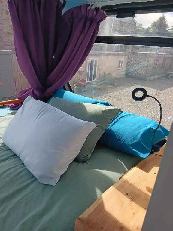 a bed with pillows sitting in front of a window at Archie The Double Decker Bus in Tain