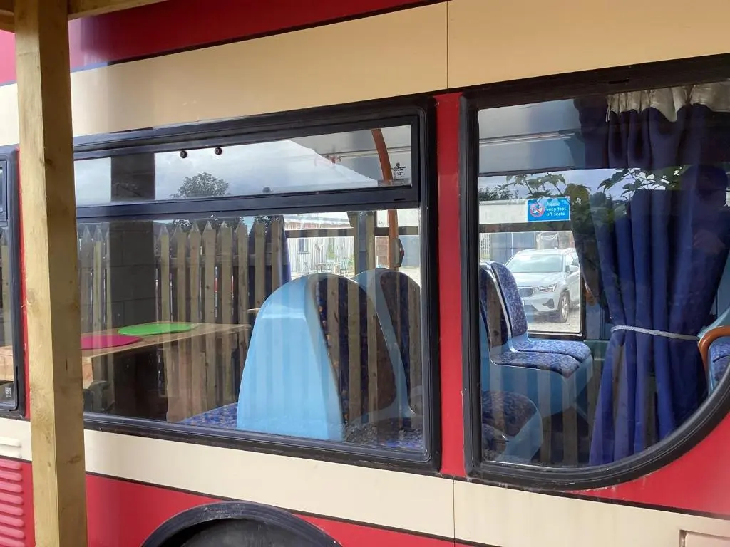 a bus with chairs and a table in the window at Archie The Double Decker Bus in Tain