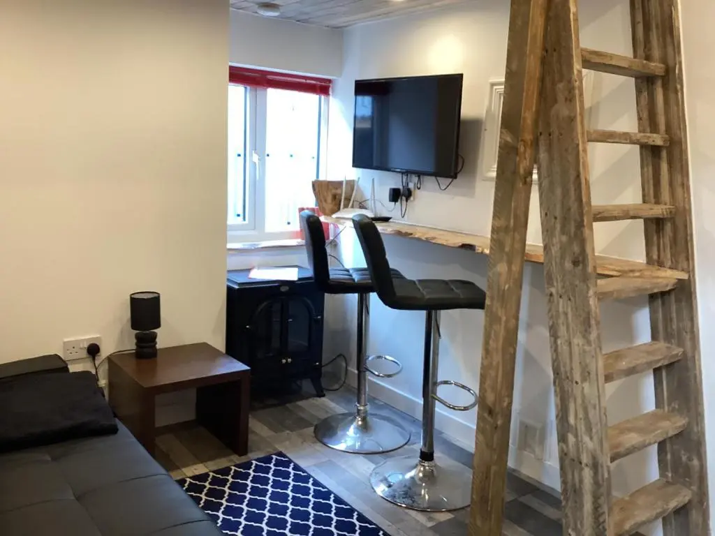 a living room with a desk with a television and a chair at The Wee Bothy in Tain