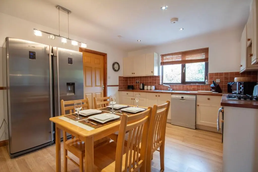 a kitchen with a table and a stainless steel refrigerator at Boutique Four Bed Holiday Home in Inverness in Inverness