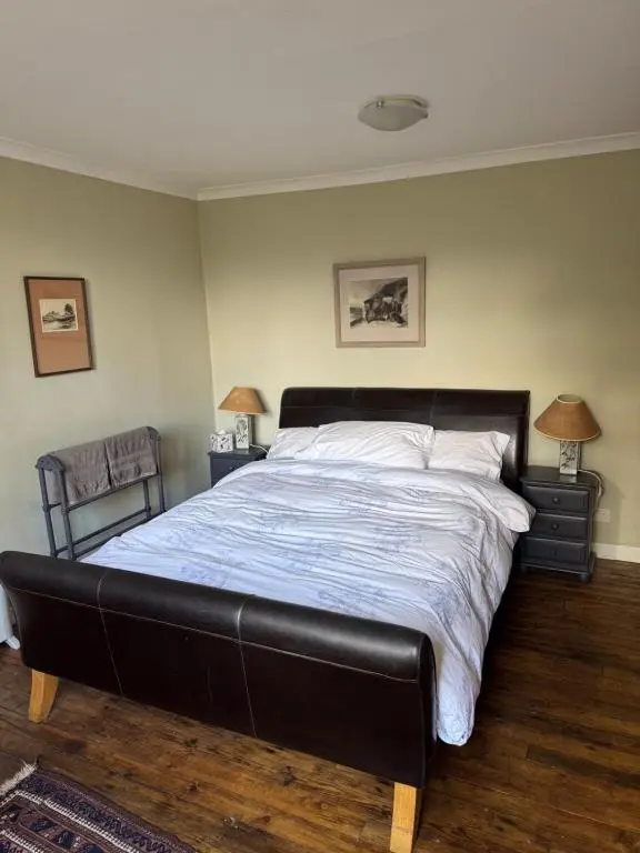 a bedroom with a large bed with a black leather headboard at Ullapool Lawyur's patch in Ullapool