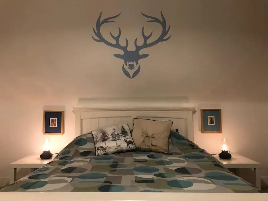 a bedroom with a bed with a deer head on the wall at Calailan Highland Seaside Retreat - Nairn in Nairn