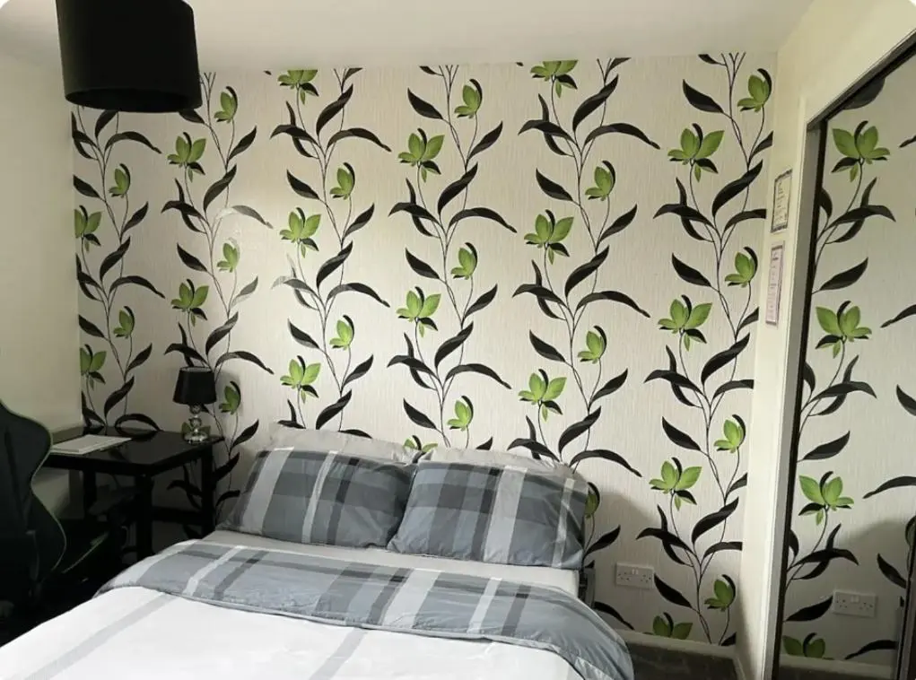 a bedroom with a bed with a wall with green flowers at Townhead Road in Inverurie