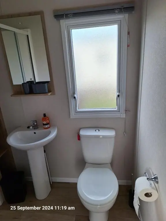 a bathroom with a toilet and a sink and a window at Lewis Sands PC114 in Lossiemouth