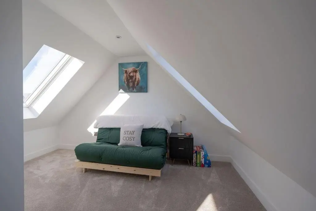 a bedroom with a green couch in a attic at Easter Cottage -4 Bed Converted Barn Cottage in Turriff