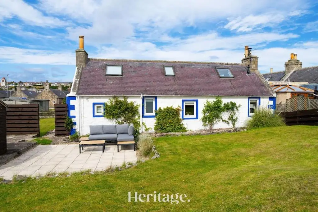 a white house with a lawn in front of it at Beach Cottage, Pet & Family Friendly Stay in Moray in Lossiemouth