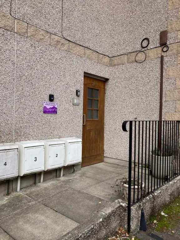a building with a door with a purple bag on it at Flat 2 at Inverness City in Inverness