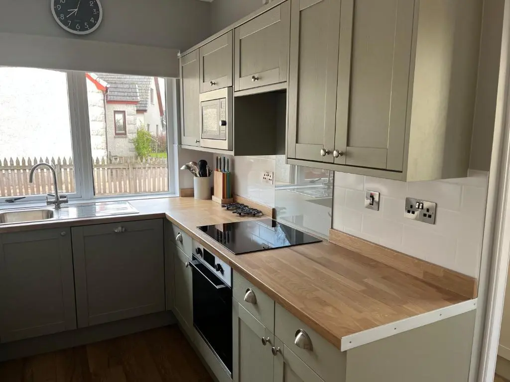 a kitchen with white cabinets and a wooden counter top at Dalfaber House Luxury holidays in the Highlands in Aviemore
