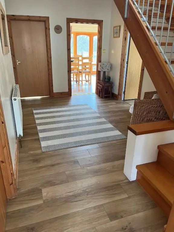 a hallway with a staircase and a living room with wood floors at Dalfaber House Luxury holidays in the Highlands in Aviemore