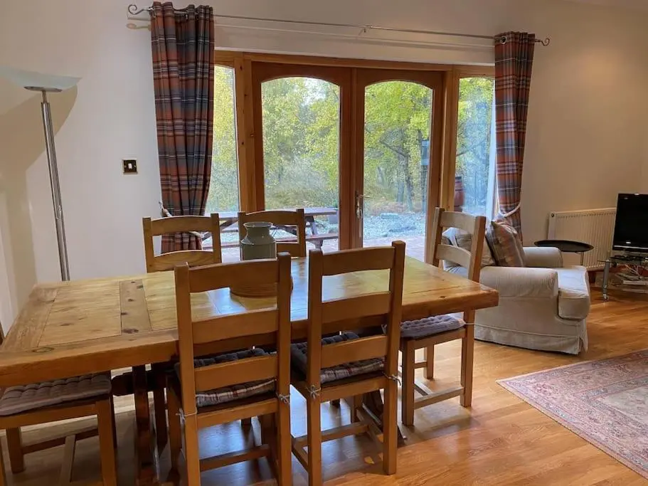 a dining room with a wooden table and chairs at Dalfaber House Luxury holidays in the Highlands in Aviemore