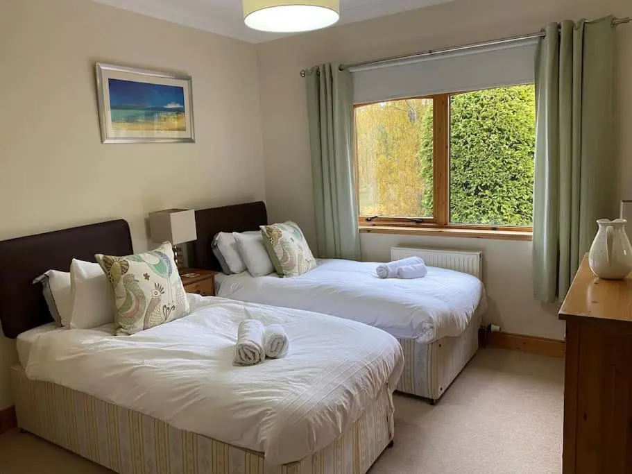 a room with two beds and a window at Dalfaber House Luxury holidays in the Highlands in Aviemore