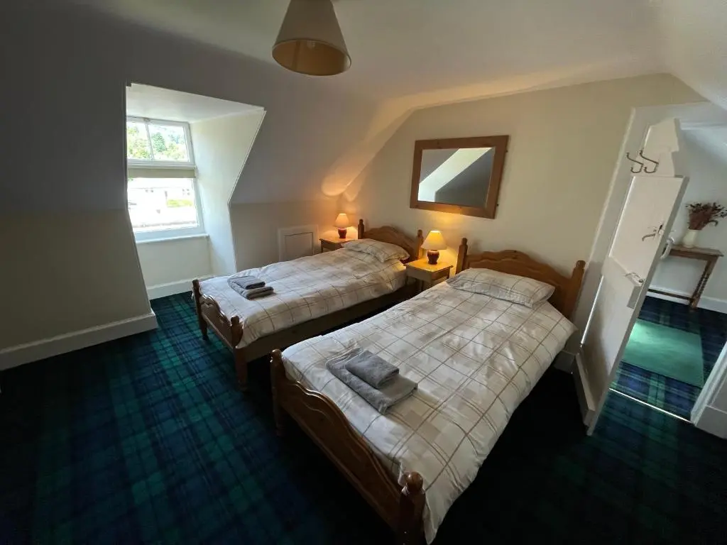 a bedroom with two beds and a window at Old Lock-keeper's Cottage in Fort Augustus