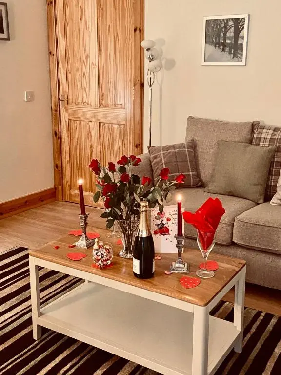 a living room with a table with flowers and candles at Dalvey Ploughmans Cottage in Forres