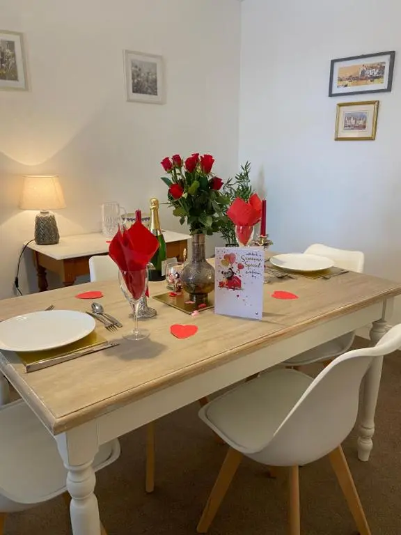 a dining room table with red roses on it at Dalvey Mill Cottage in Forres