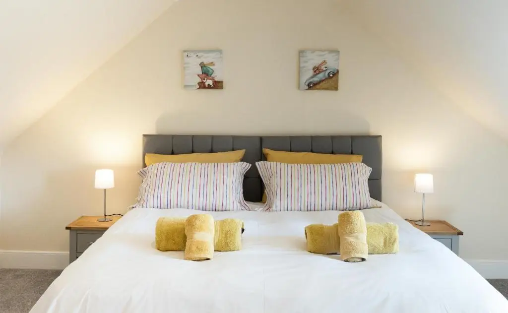 a bedroom with a white bed with two lamps at Dalvey Abbotshill Farm House in Forres