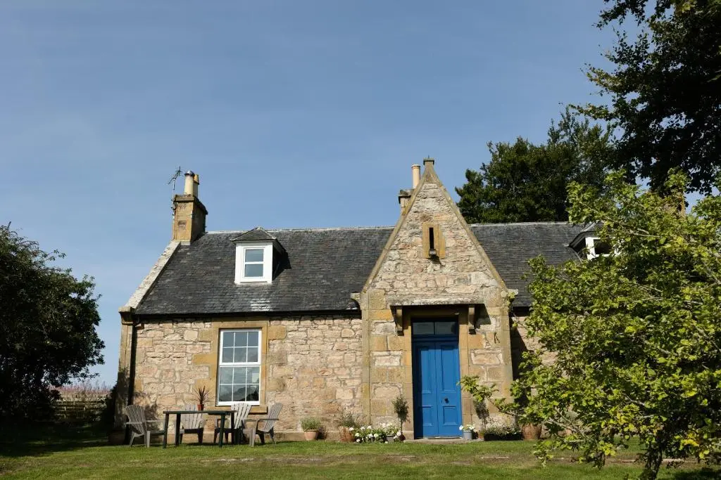 an old stone house with a blue door at Dalvey Abbotshill Farm House in Forres